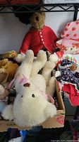 Shelf display showing multiple plush toys including white rabbit, teddy bears and dolls