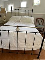 Full view of 3/4 sized antique iron bed with mattress and white sheets, pillows included but duvet and pillows excluded in sale.