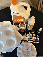 Photo showing assortment of art supplies including tubes of Craft Smart paint, plastic paint trays, a jug of Flood Floetrol, and other paints/mediums.