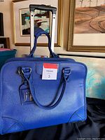 Front view of blue wheeled briefcase with carry handles and wheels visible on bottom