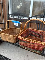 Two large wicker baskets placed on a black metal chair, one natural wicker and one multicolored wicker basket
