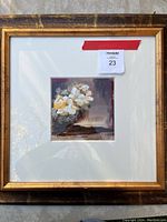 Framed oil painting of white and yellow flowers shown with a gold textured frame and white matting.
