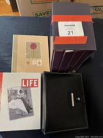 Seven small photo albums on a dark surface, featuring one LIFE branded album, one beige album with floral design, five purple hardcover albums, and one black album with snap closure.