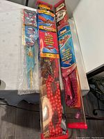 Three new kites packaged together on a table showing colorful designs and product labels.