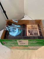 Top view of a green cardboard box labeled '70 CDs' containing assorted music CDs, including 'Paul Robeson: The Power of His Voice'
