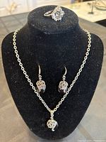 Necklace displayed on black jewelry bust with matching earrings and ring shown on top of bust.