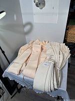 Overview of cream and beige pleated curtains folded on a table showing two different sizes