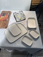 Photo showing the grilling plank on left, metal trivet top center, and stoneware dishes arranged around them on white tablecloth
