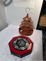 Wooden Japanese birdcage and octagonal Asian lacquered trinket box placed on a white surface