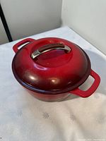 Top view of closed red KitchenAid Dutch oven showing lid with metal handle and branding.