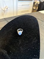 Single sterling silver ring with opal stone displayed on black velvet background.