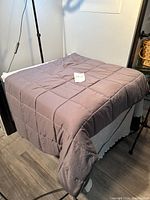 Gray weighted blanket spread on a chair, shows full size and thickness.