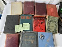 Overview of 11 antique/vintage books showing various colors and wear on covers, two with visible sticky notes about contents and condition