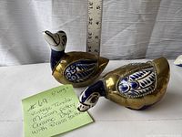 Two vintage Tonala duck ceramic figures with blue and white porcelain bodies and brass feathers, shown with ruler for scale.