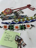 Five assorted vintage beaded jewelry items arranged on white surface with a handwritten note indicating some pieces are damaged and vintage