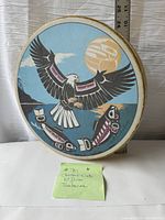 Front view of the hoop drum showing full eagle and salmon design under a pale yellow moon or sun with a ruler for scale.