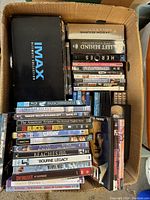Top view of the box showing IMAX Ultimate Collection, Jason Bourne Collection, Heroes Season 2, Left Behind Collection and assorted DVDs arranged vertically and horizontally.
