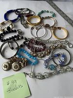 Photo showing a varied assortment of bracelets including bangles, beaded, chain link, and decorative pieces with a ruler for scale.