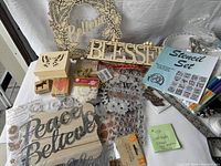 Craft supply lot including wooden signs 'Believe', 'Blessed', metal word cutouts 'Peace' and 'Believe', alphabet stamp sheets, small wooden block stamps, stencil set, and embellishments.