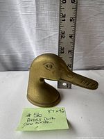 Photo of vintage brass duck cane handle showing size against measuring tape, 3 inches tall, 4 inches wide.