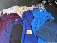 Overview of assorted women's plus size clothing including long sleeved shirts, tank tops, and blouses in various colors and styles.