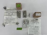 Photo of three specialty door hinges and all related items including original packaging, instructions, and screws on white background.