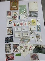 Full view of assorted vintage cards, gift tags, and art cards laid out on a white surface showing various themed illustrations and packaging.