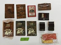 Top view of all 11 items arranged on white background showing 6 passport covers with embossed Egyptian motifs, 2 wallets (brown and black), 2 cigarette pack holders, and 1 eyeglass case.