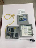 Full view of Hunter ICC-800PC controller unit with enclosure open showing main control panel, wiring terminals, attached yellow power cord, and manual above.