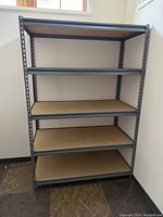 Full view of 6 ft high metal shelving rack with 5 particle board shelves in place.