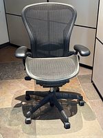 Front view of chair showing mesh seat and back, arm pads and base