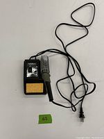 Radio Shack soldering iron power base with soldering iron attached, metal spiral holder, and cleaning sponge.