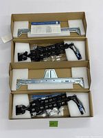 Two Dell 1U cable management arm kits unboxed showing metal brackets, black plastic articulated arms and installation instructions inside foam-padded cardboard boxes