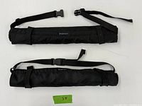 Two black winter bum protectors rolled and secured with adjustable waist straps.