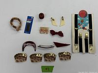 Assorted vintage personal decorative items laid out on white background including barrettes, hair clasps, bracelet, earrings, and suspenders.