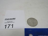 Photo showing the silver half dollar coin next to a MaxSold lot card and a ruler for scale.