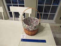 Side view of the Longaberger basket with floral fabric liner and handle, showing the basket weaving and fabric details.