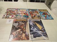 Six comic books laid out on a table with visible colorful covers showing Ironman and Hawkman characters