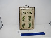 Front view of the slate herbs sign with ruler for scale, showing the four herb illustrations and hanging hook.