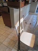 View of two pool sticks standing upright behind a chair in a home setting.