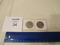 Two Franklin Half Dollar coins side by side for scale with a ruler below them showing size.