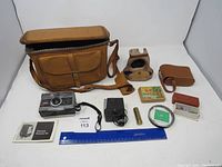 Full view of the vintage camera lot including camera, leather cases, light timer, batteries, filter, and manual.