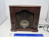 Front view of the vintage General Electric wooden tabletop radio with decorative speaker grill and control knobs on each side.