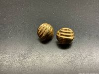 Two round gold stud earrings with spiral grooves on black background