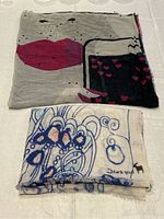 Two folded scarves stacked to show patterns and colors