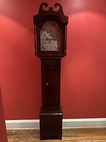 Full front view of tall-case clock against red wall