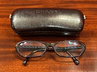 Chanel brown leather eyeglass case with embossed logo and eyeglasses in front