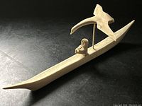 Full view of bone carving on black background showing entire length and shape of boat.