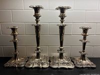 Front view of four candlesticks against white tiled background