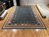 Full view of the area rug laid flat on a wooden floor showing its size and design.